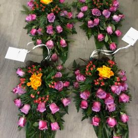 Neljä hautajaiskimppua violeteilla ja keltaisilla kukilla