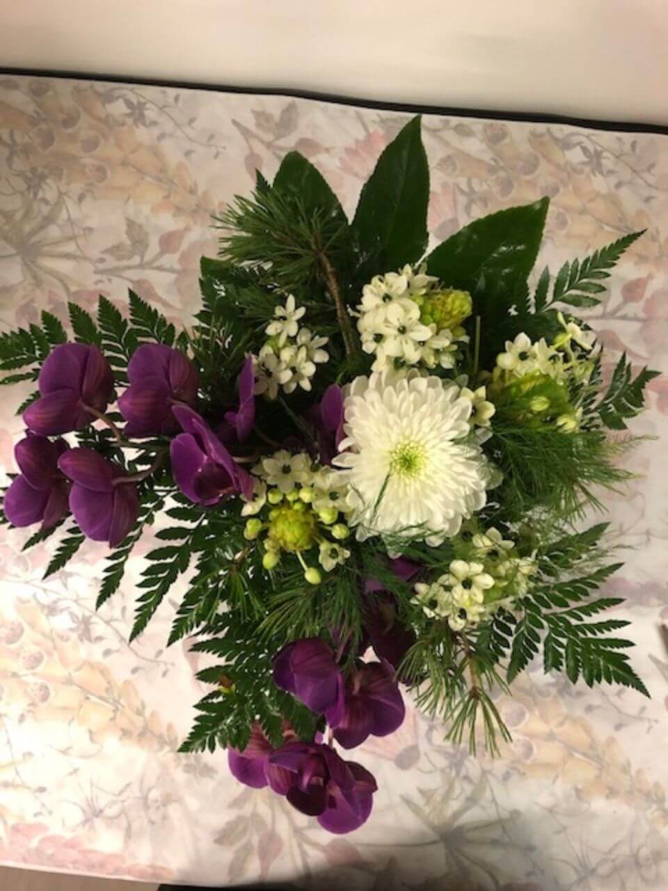 Hautajaiskimppu valkoisilla ja violeteilla kukilla
